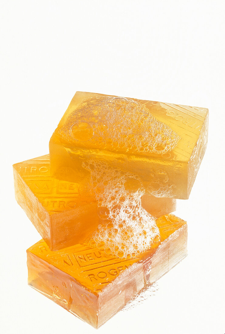 Three orange soaps with foam stacked on white background