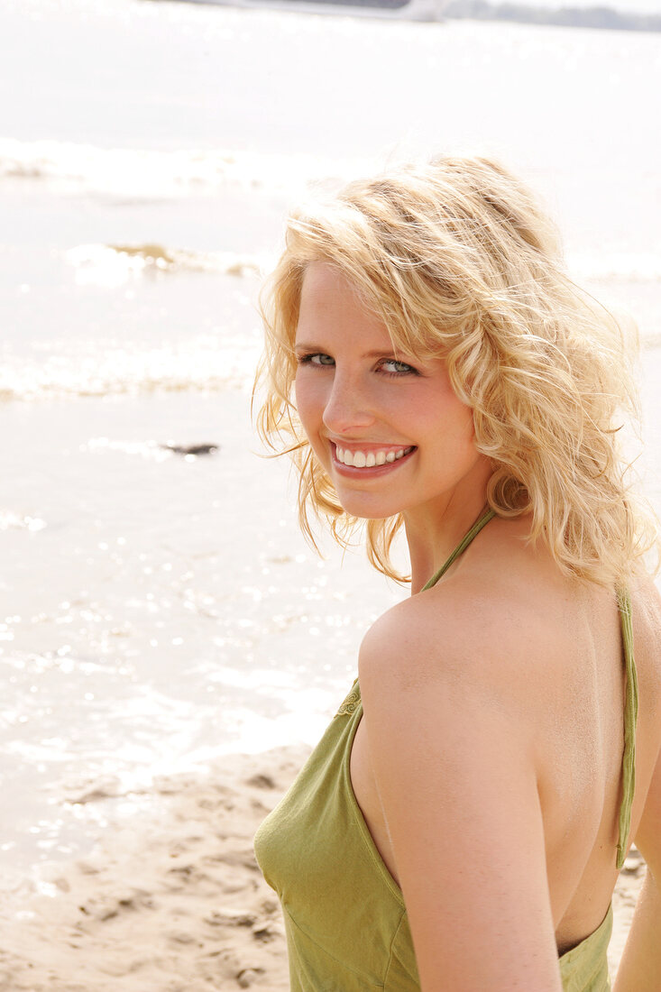 Portrait of beautiful blonde woman wearing green halter top, smiling