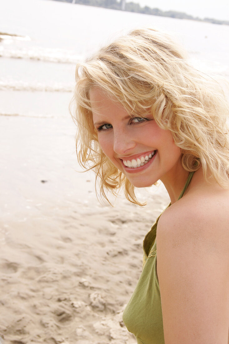 Berit, Frau mit grünem Sonnentop am Strand, lacht in die Kamera