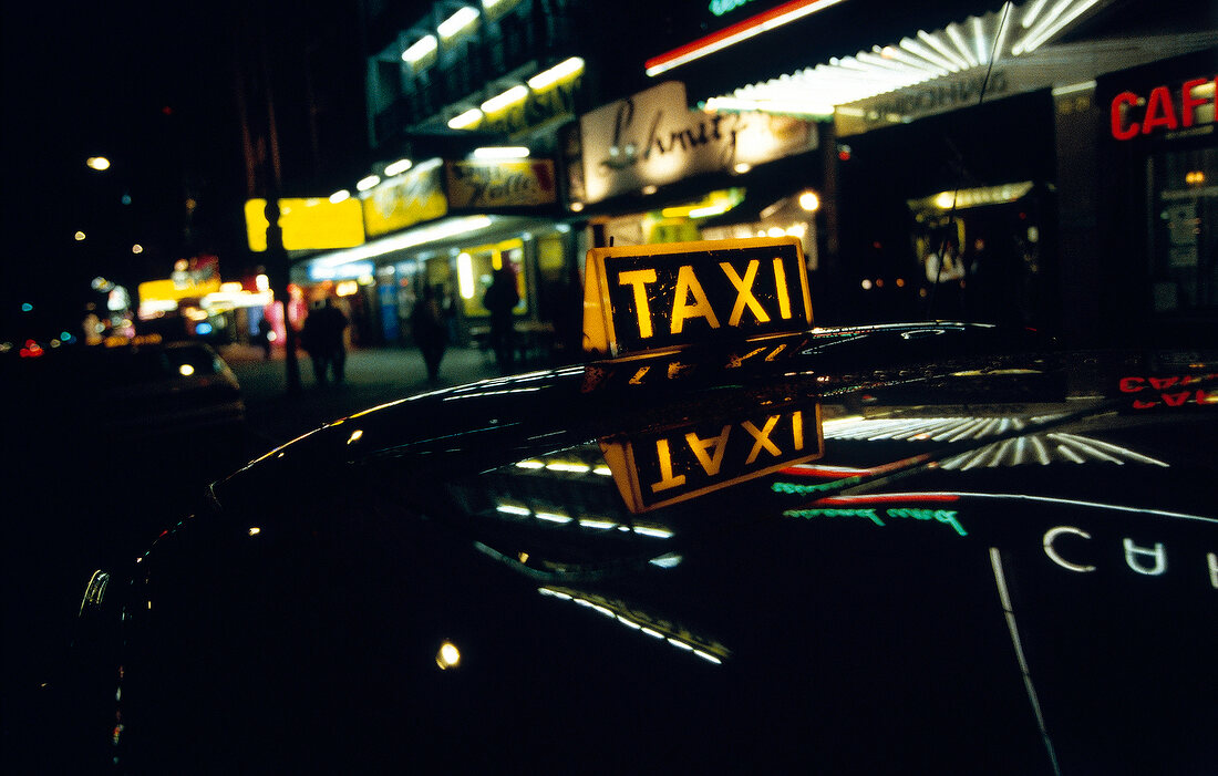 Taxi at night in entertainment district of city with colourful lights
