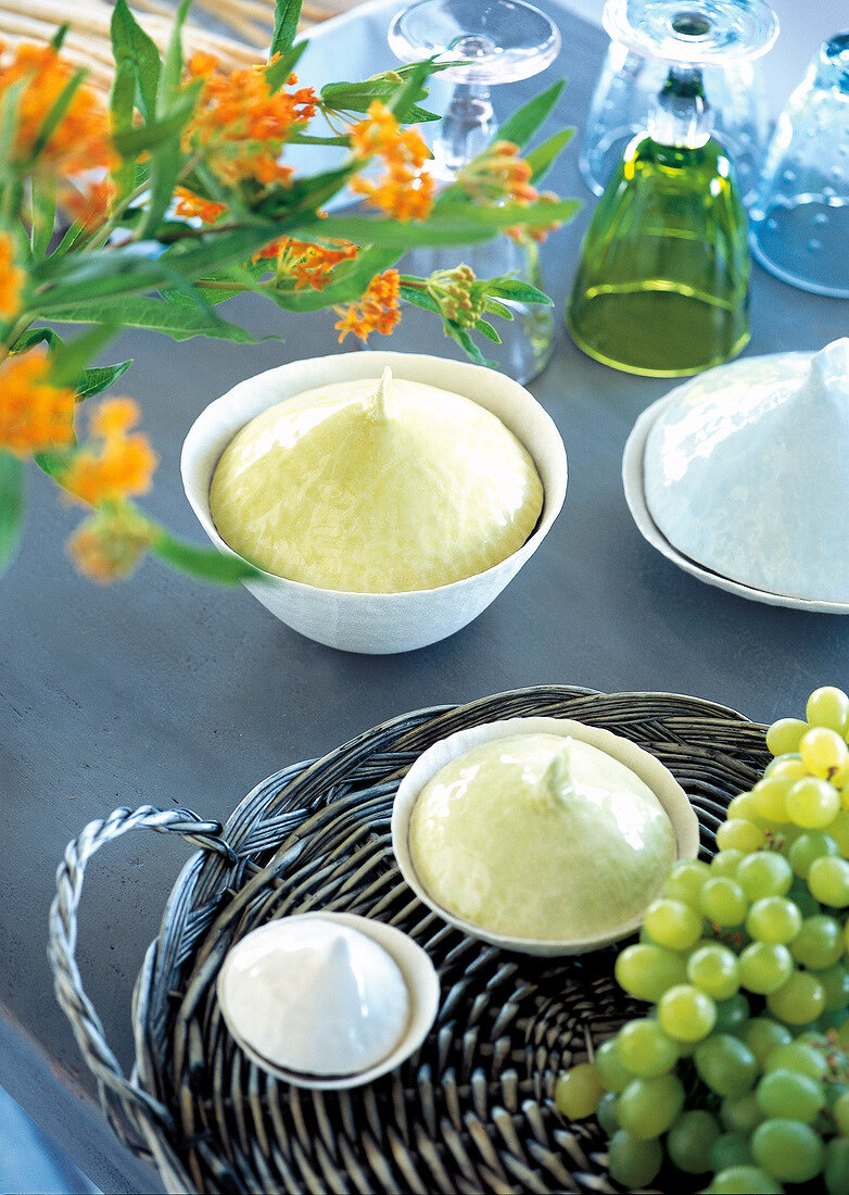 White porcelain bowls, flowers, wicker tray, fruit and glasses on table