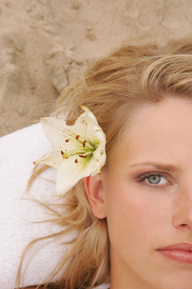 Close-up of pretty gray eyed blonde woman with flower in her hair