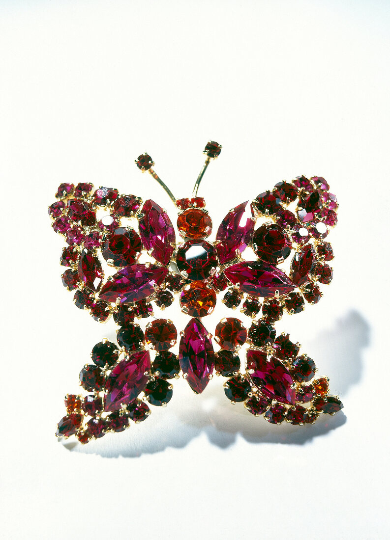 Close-up of red butterfly shaped brooch on white background