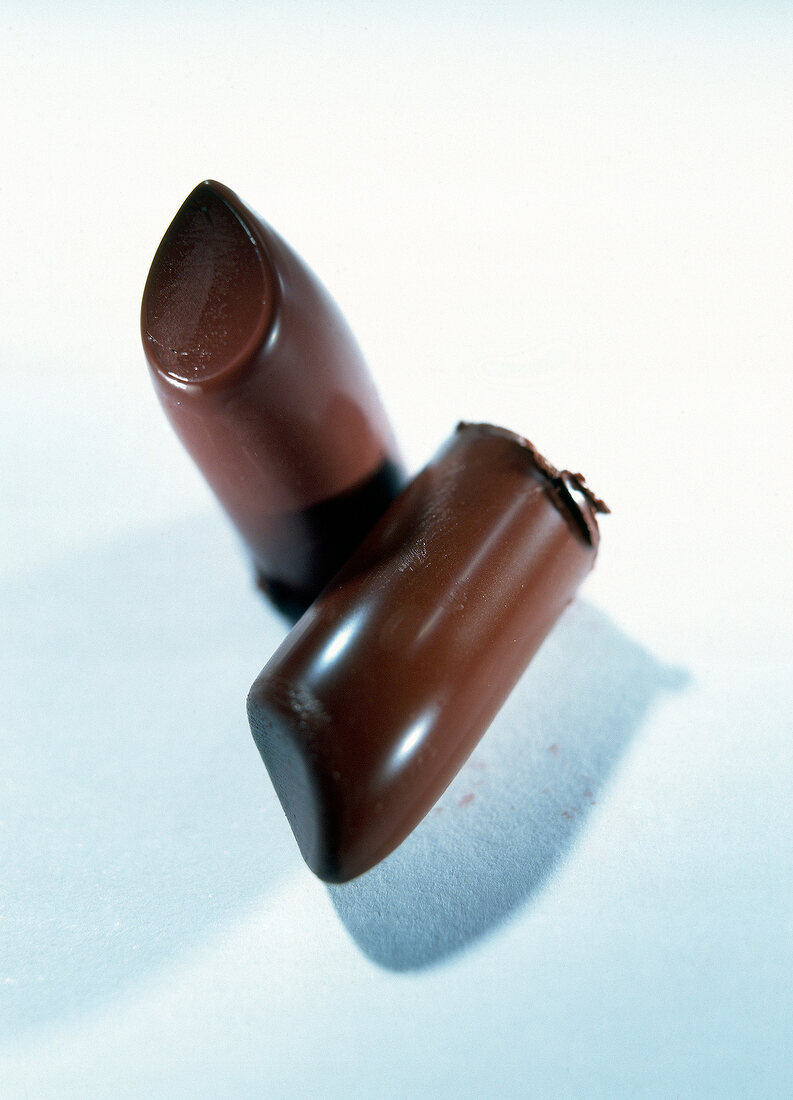 Close-up of two pieces of brown lipstick on white background