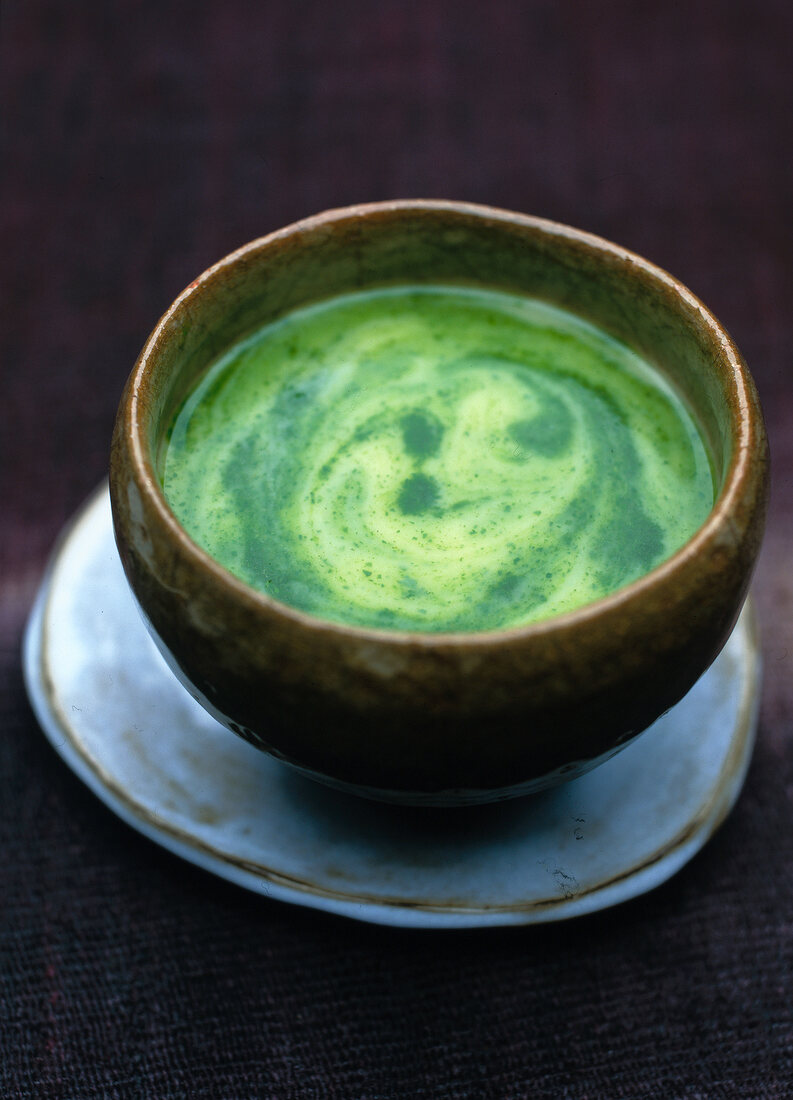 Close-up of potato and watercress soup in rustic bowl