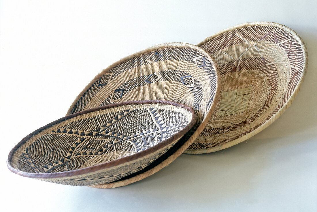 Close-up of three shallow bowls made of steppe grass with ornament design in ethnic style