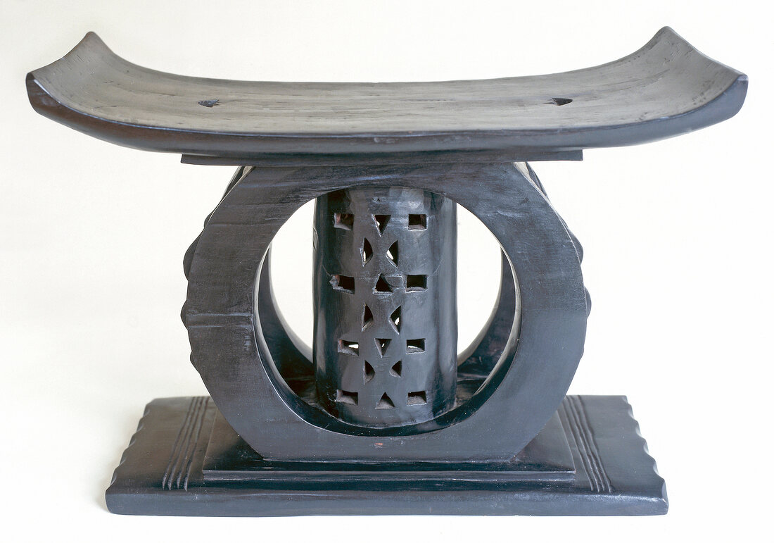 Close-up of ashanti stool made of black patina with wooden carving on white background