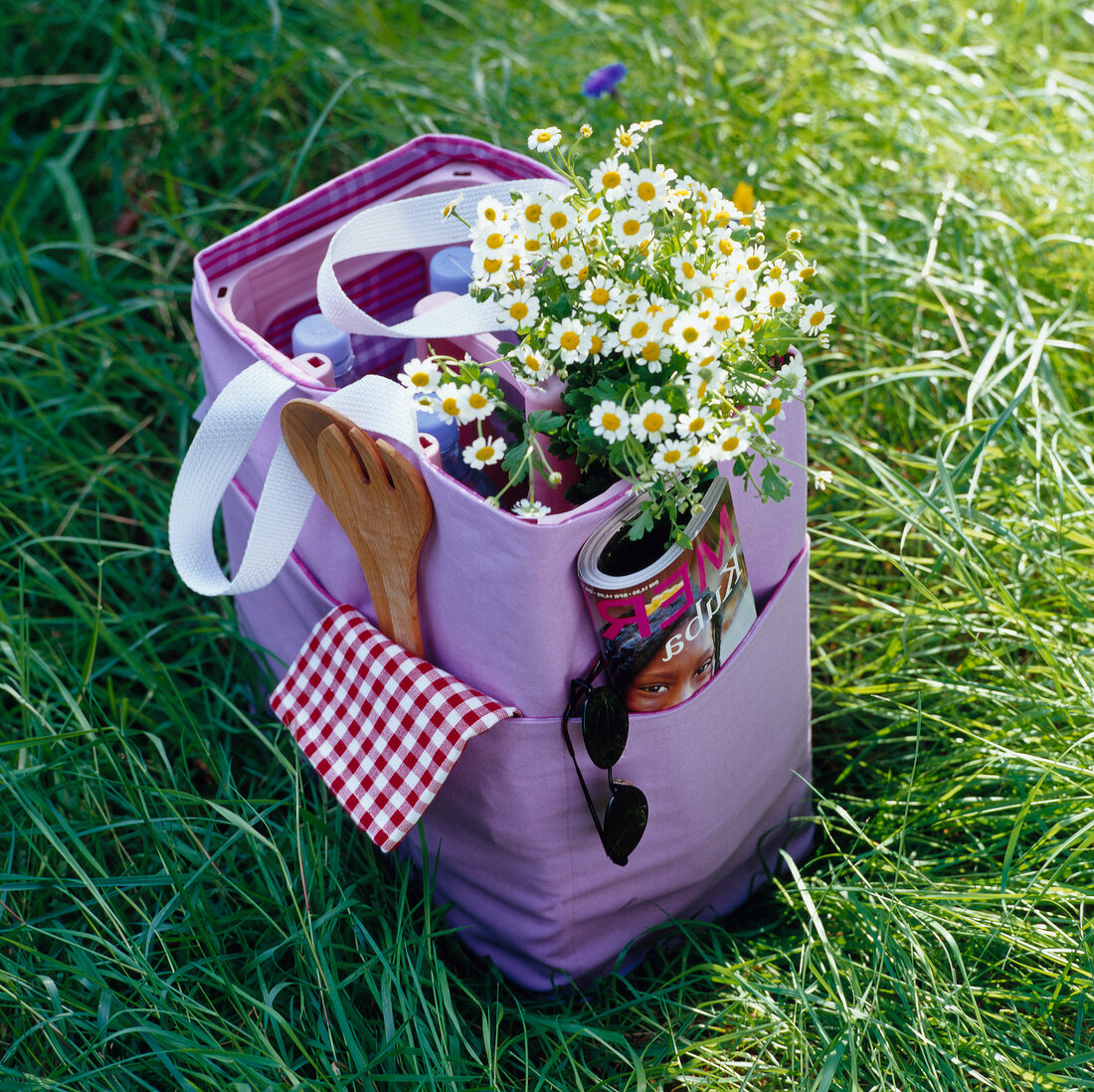 Packed picnic bag with flowers, sunglasses, journal and bottles