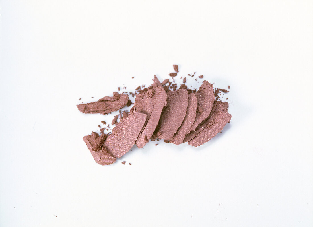 Close-up of crushed brown rouge on white background