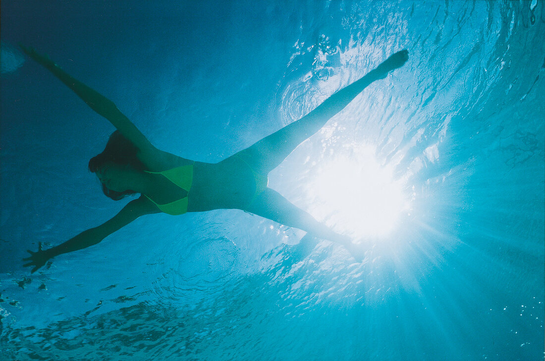 Unterwasser-Foto: brünette Frau im Bikini in Gelb beim Schwimmen, blau