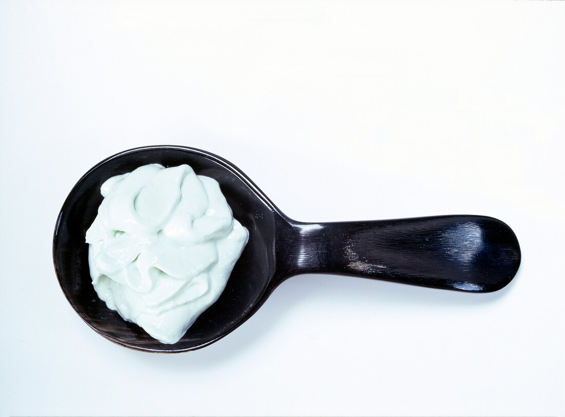 Close-up of mint coloured dollop face mask in horn spoon on white background