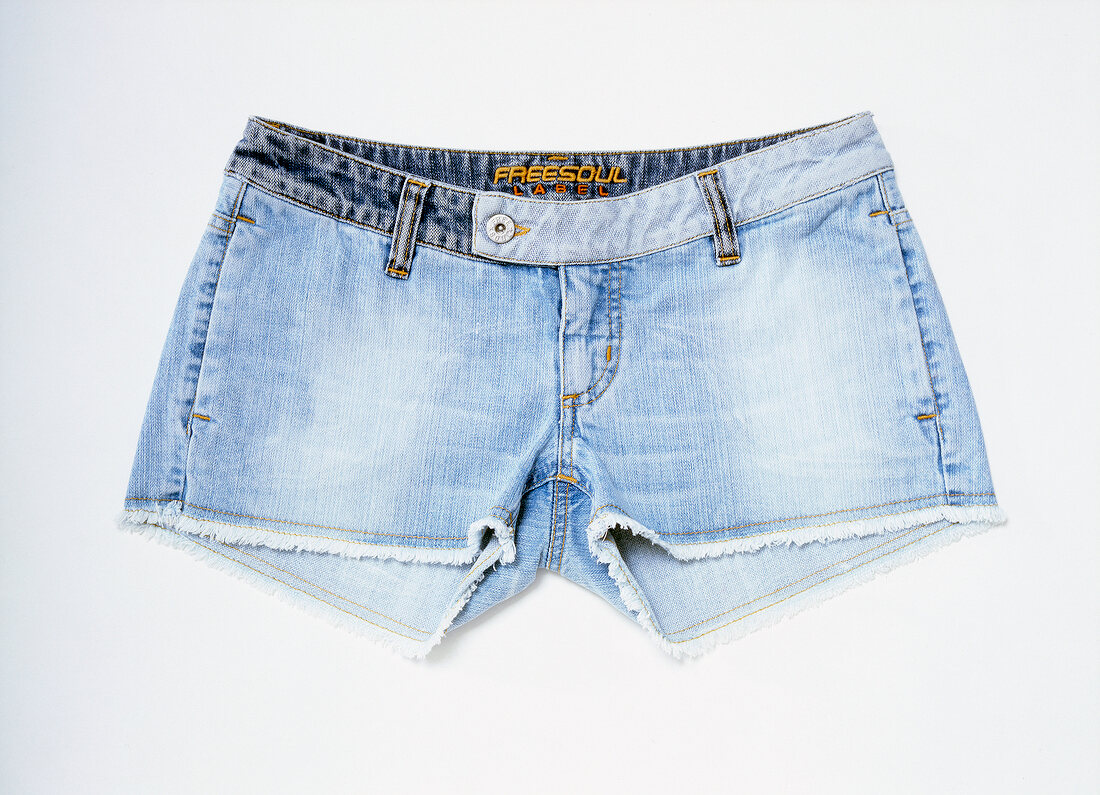 Close-up of pair of blue denim hot pants on white background