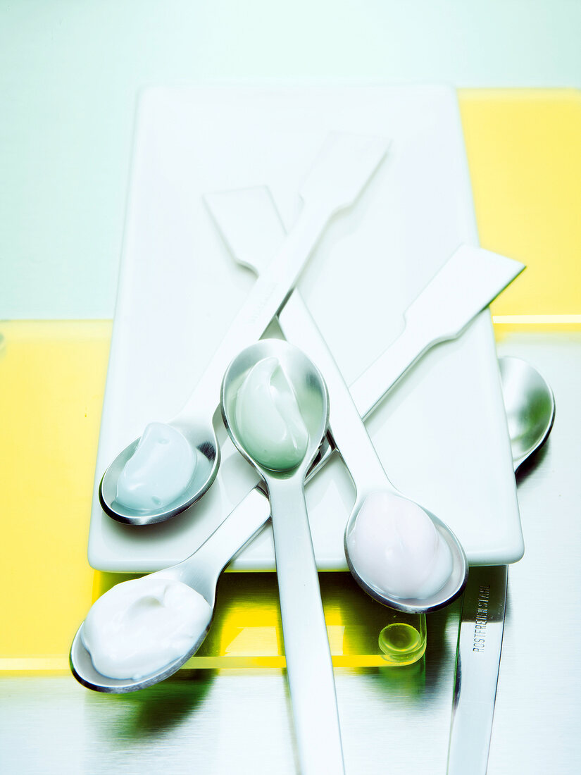 Four teaspoons with cream samples on it