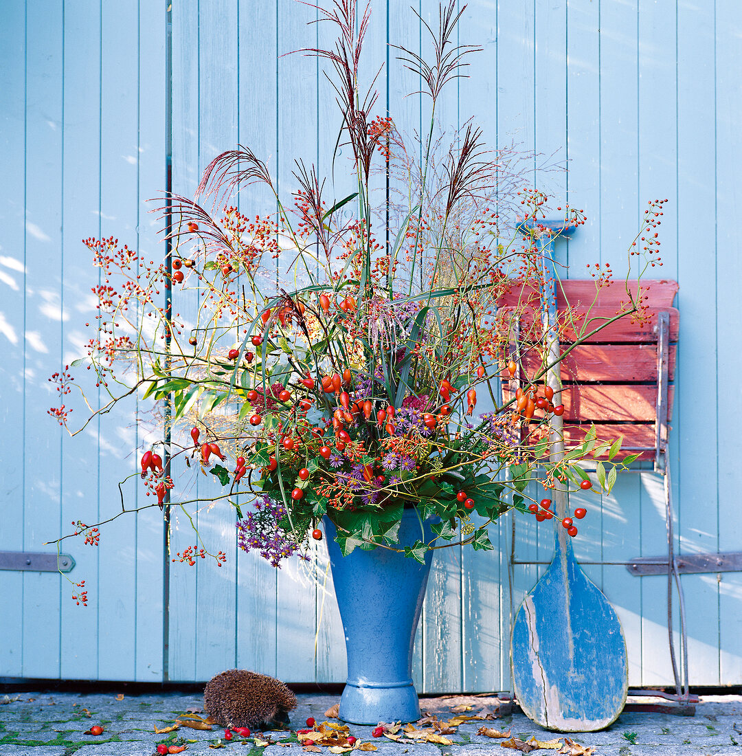 Blue vase with rose hips, ivy and autumn asters