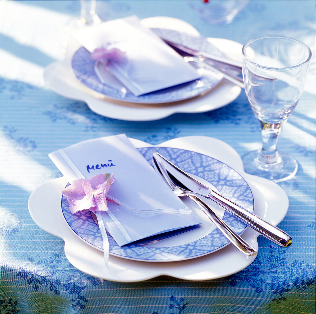 Tischgedeck in Blau-Weiß, Menükarte + Besteck auf Teller, Glas
