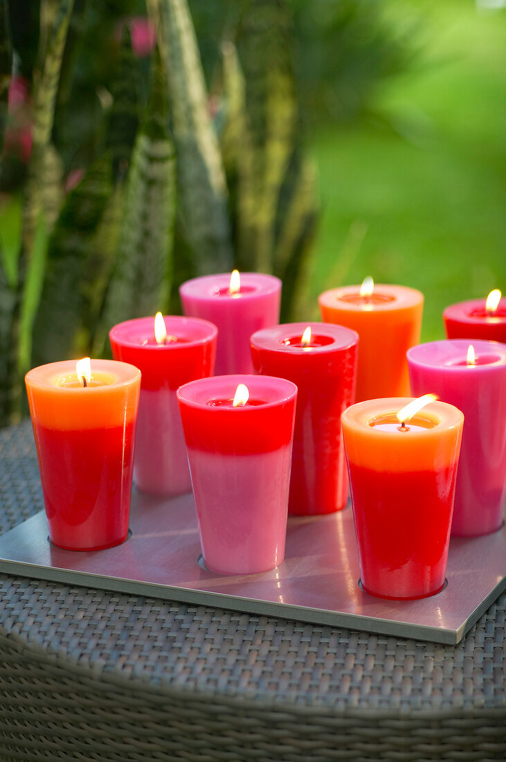 Two different coloured lit candles on tray