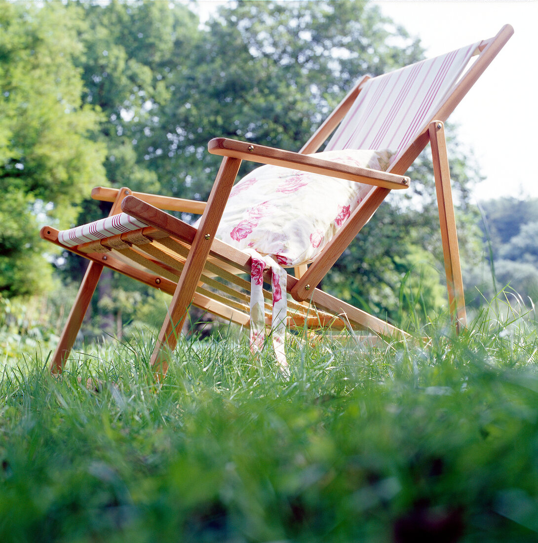 Close-up of wooden sling chair with cushion in garden