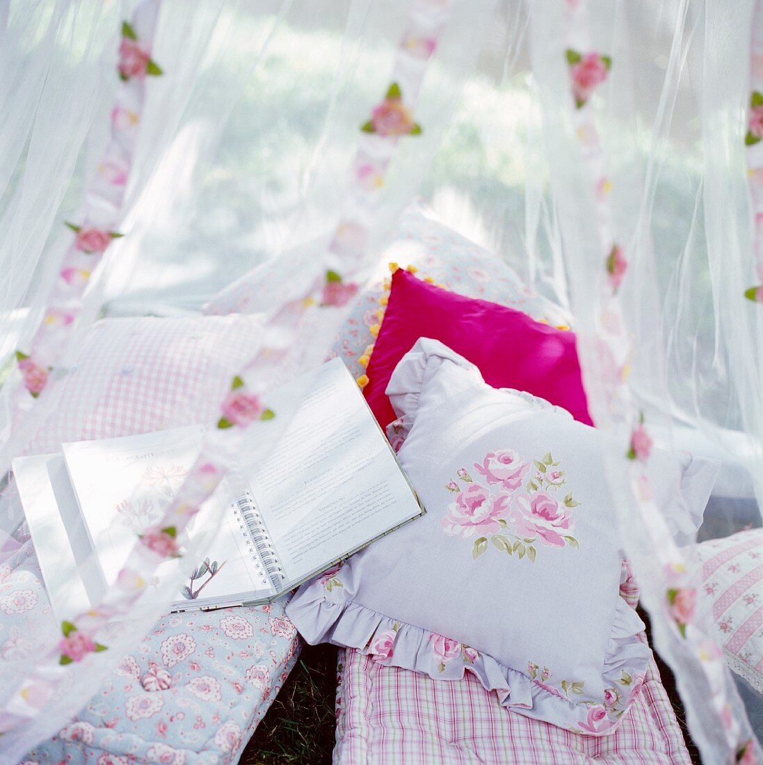 A romantic seating area with cushions under a mosquito net