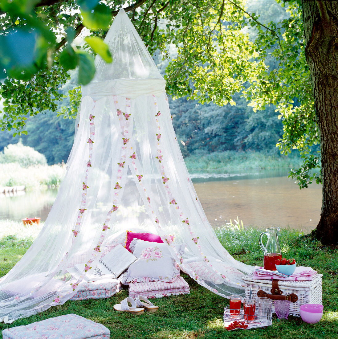 Canopy in garden with cushions and basket on grass