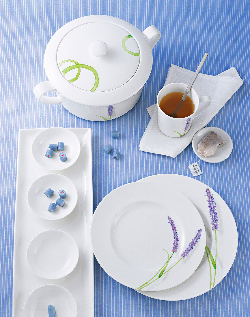 White tea cup and tableware with floral decor on blue tablecloth