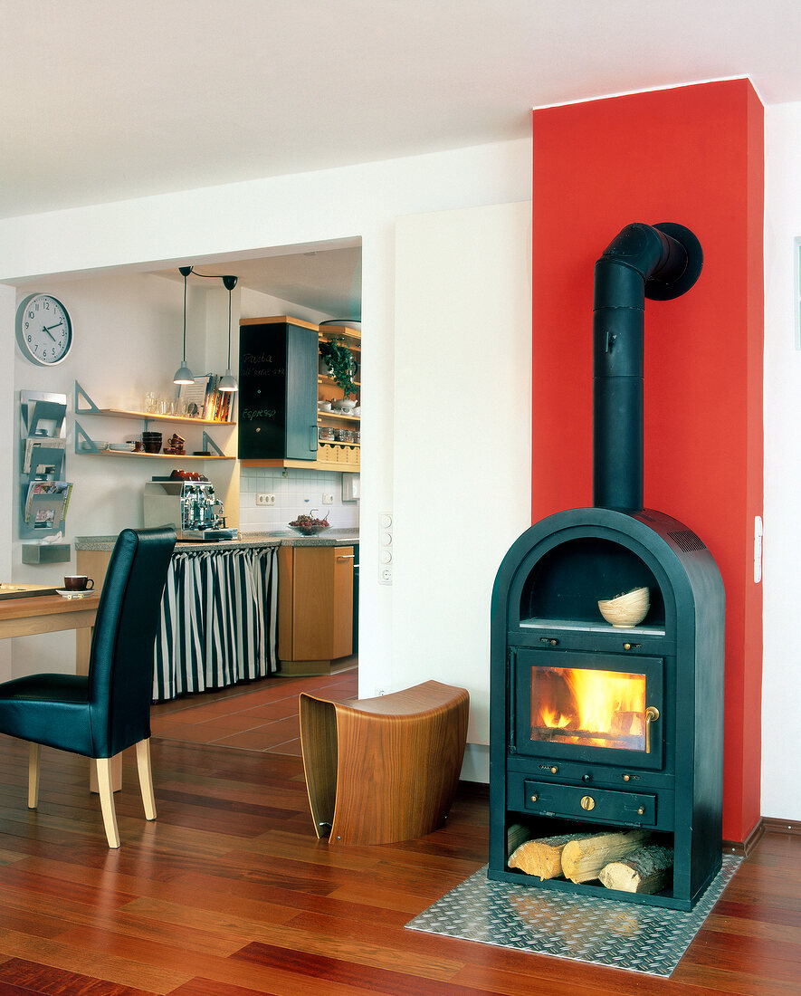 Stove with fire and stove pipe against red wall