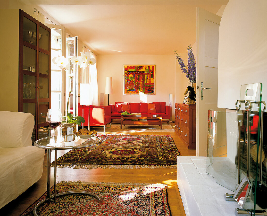 Wohnzimmer mit Orientteppichen, rote Sofas, Kamin, Terrassentür