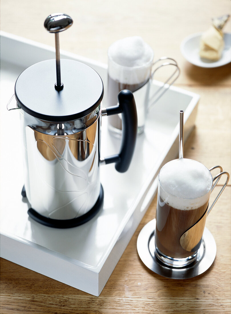 Kaffeebereiter und zwei Kaffeegläser mit viel Milchschaum. x