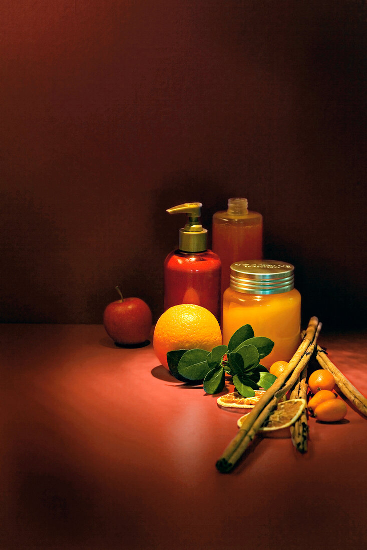 Oil of macadamia nut, orange, apple, kumquat, cinnamon sticks and shower gel on floor