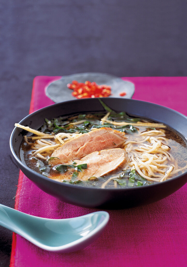 Asian noodle soup served with juicy roasted pork in bowl