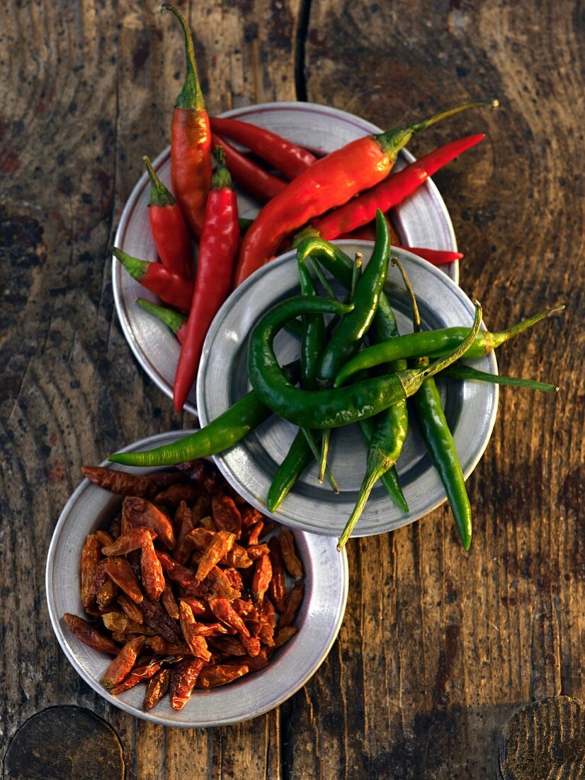 Plates of fresh and dried chilli peppers (seen from above)
