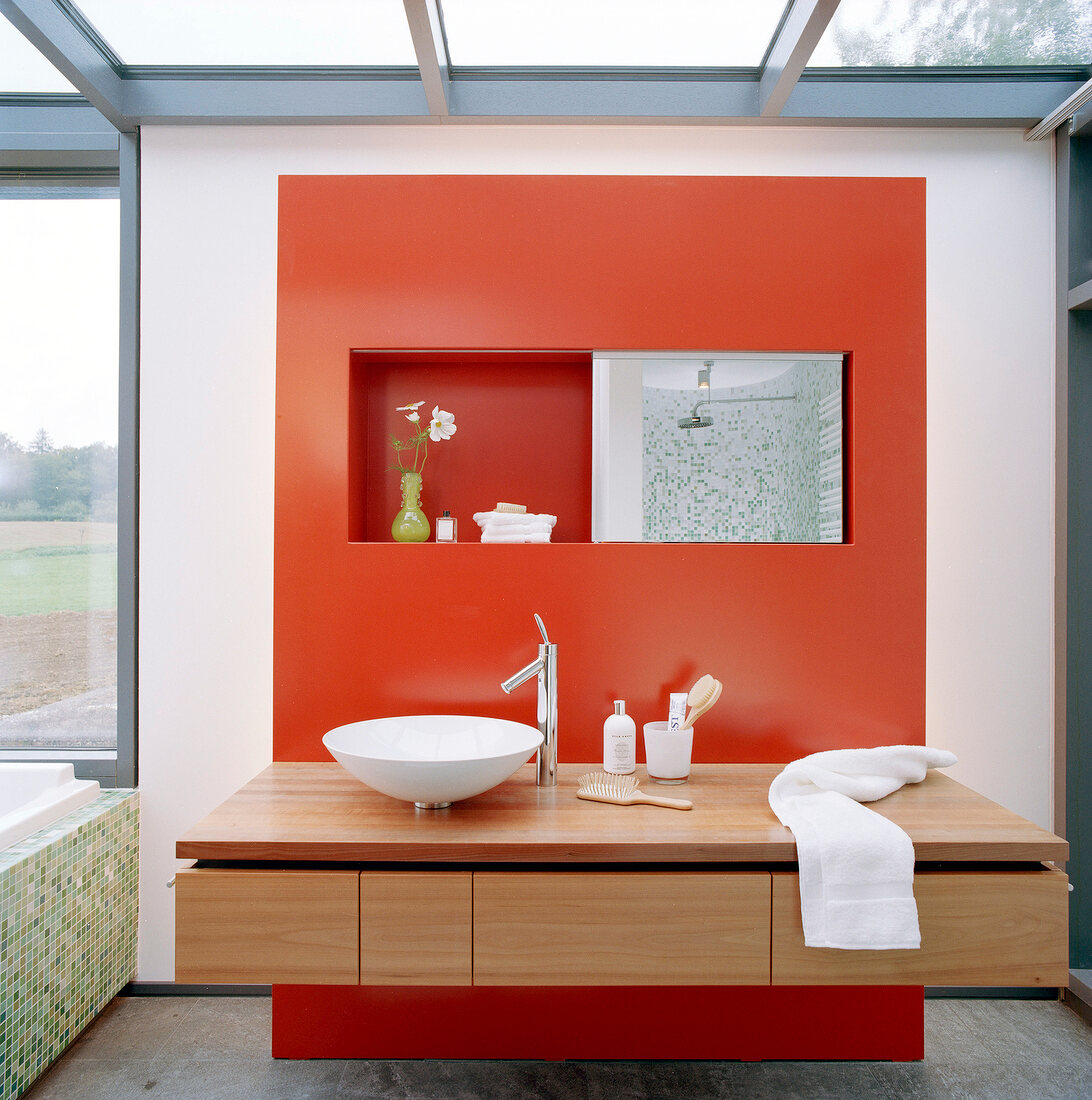 Waschtisch in einem modernen Bad mit Fensterfront und roter Wand.
