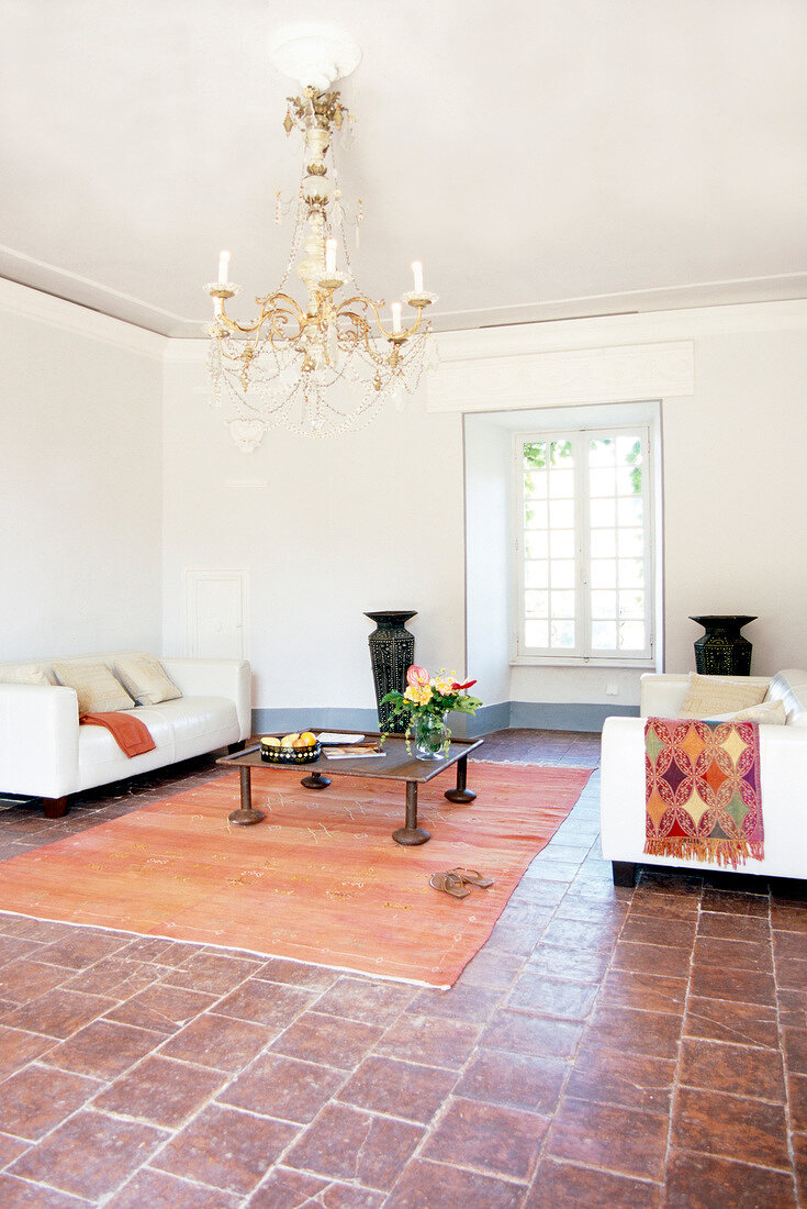 Large living room with hanging chandelier and terracotta tiles with furnitures