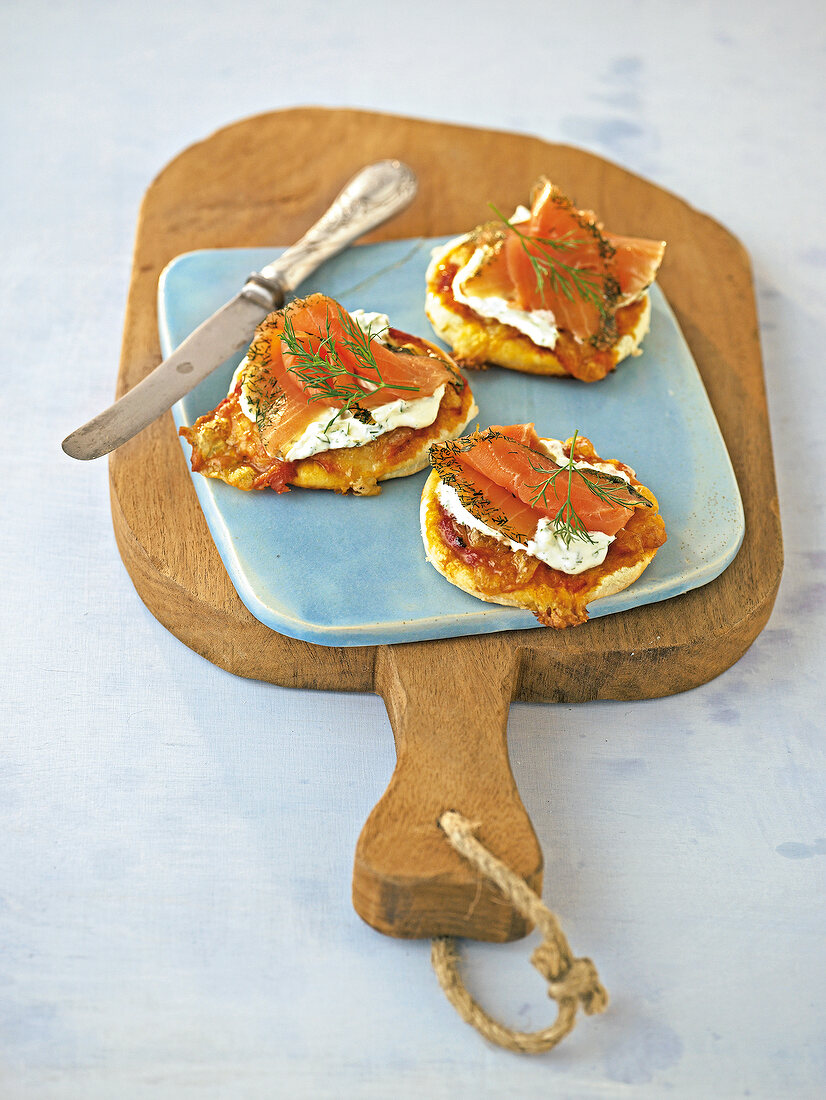 Mini-pizzas and gravlax with knife on chopping board