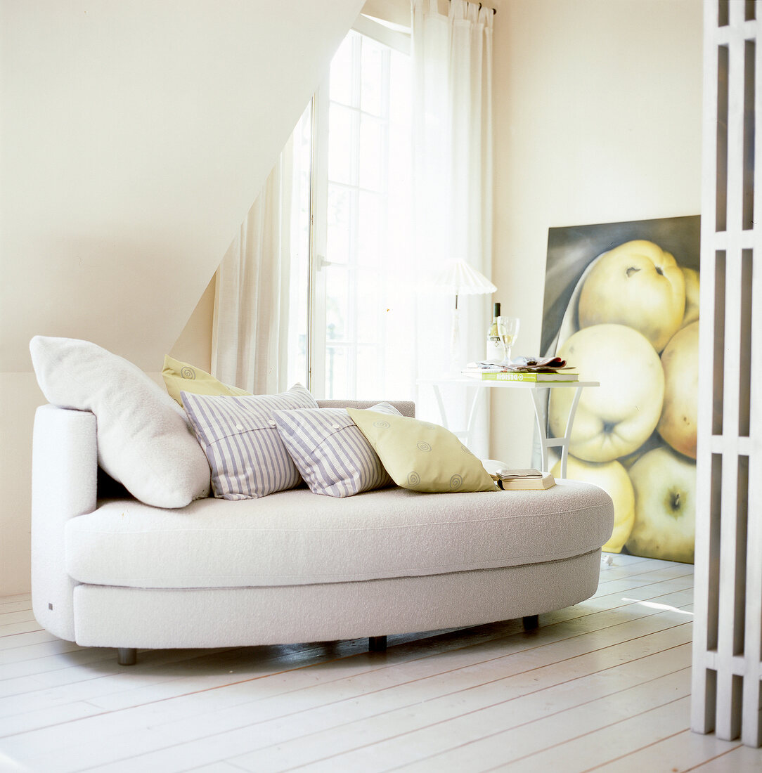 Sofa in Beige auf weißen Holzdielen, großes Poster m. Apfelmotiv