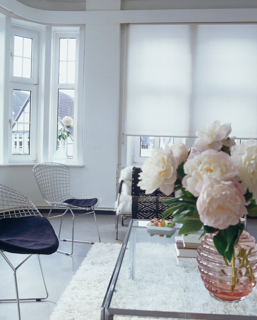 Glastisch und Metallstühle im Wohnzimmer in Weiß