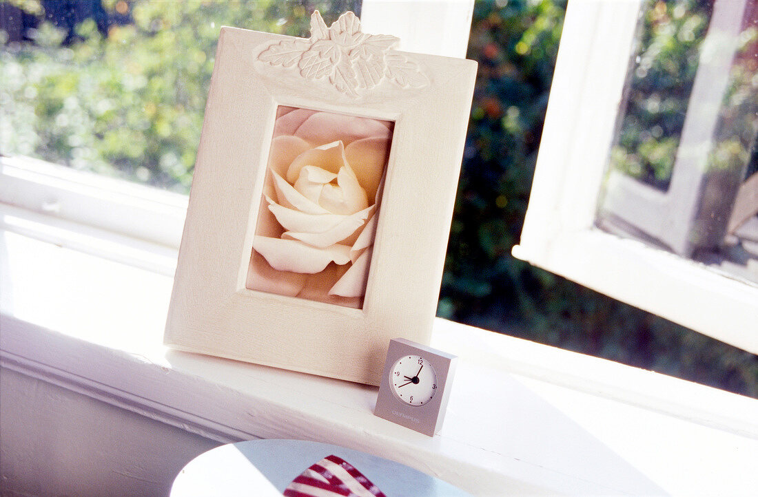 Wooden photo frame and alarm clock on window sill