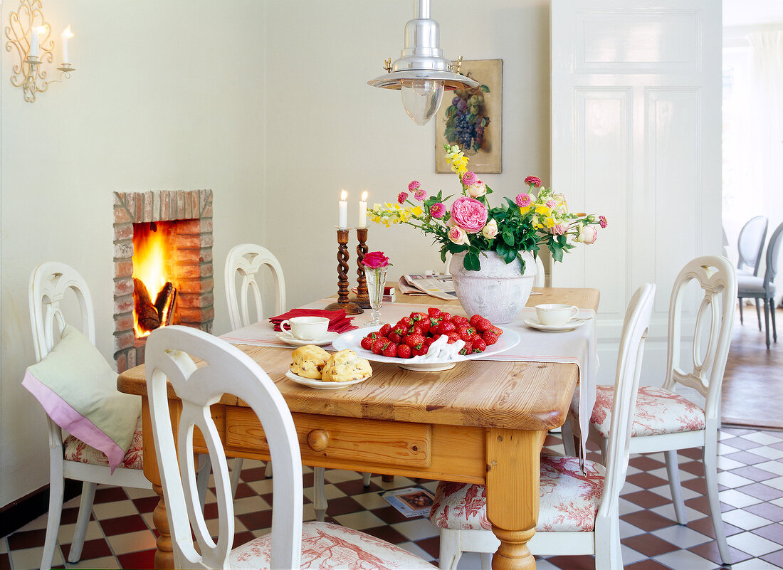 Wooden table with berries and flower pot next to fireplace