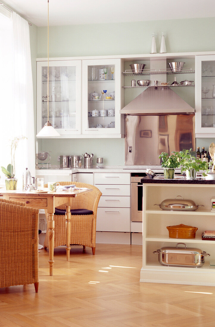 Einblick in die Küche, weiße Einbauküche, Holztisch und Korbstühle.