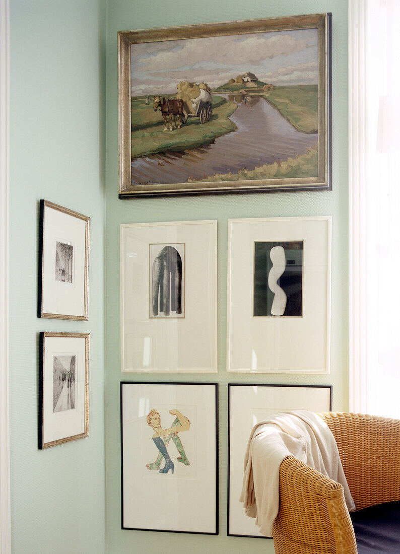 Wicker chair against various framed pictures on the wall