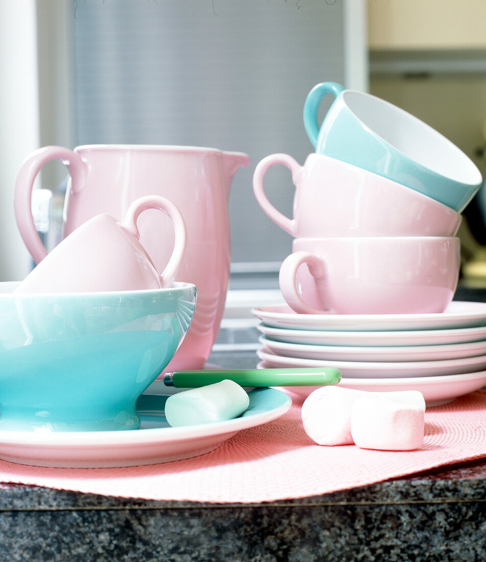 Stack of cups and saucers in light pink and light blue colour on table