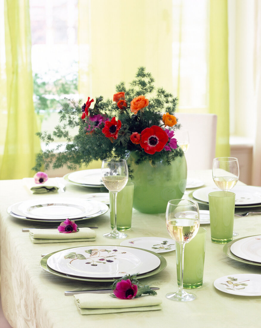 Gedeckter Tisch mit Details in Grün und Blumendeko in Rot, sommerlich