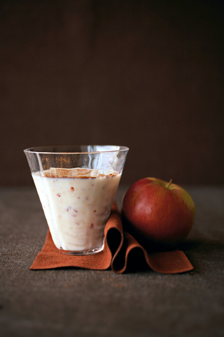 Glass of apple milkshake with apple on table mat