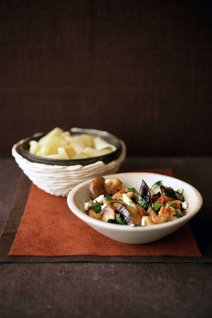 Mushroom ragout with boiled tagliatelle in bowls on table mat