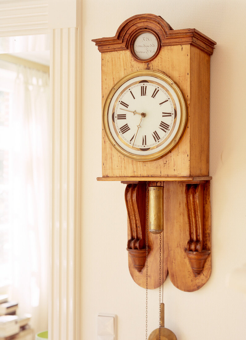Wooden pendulum clock on the wall