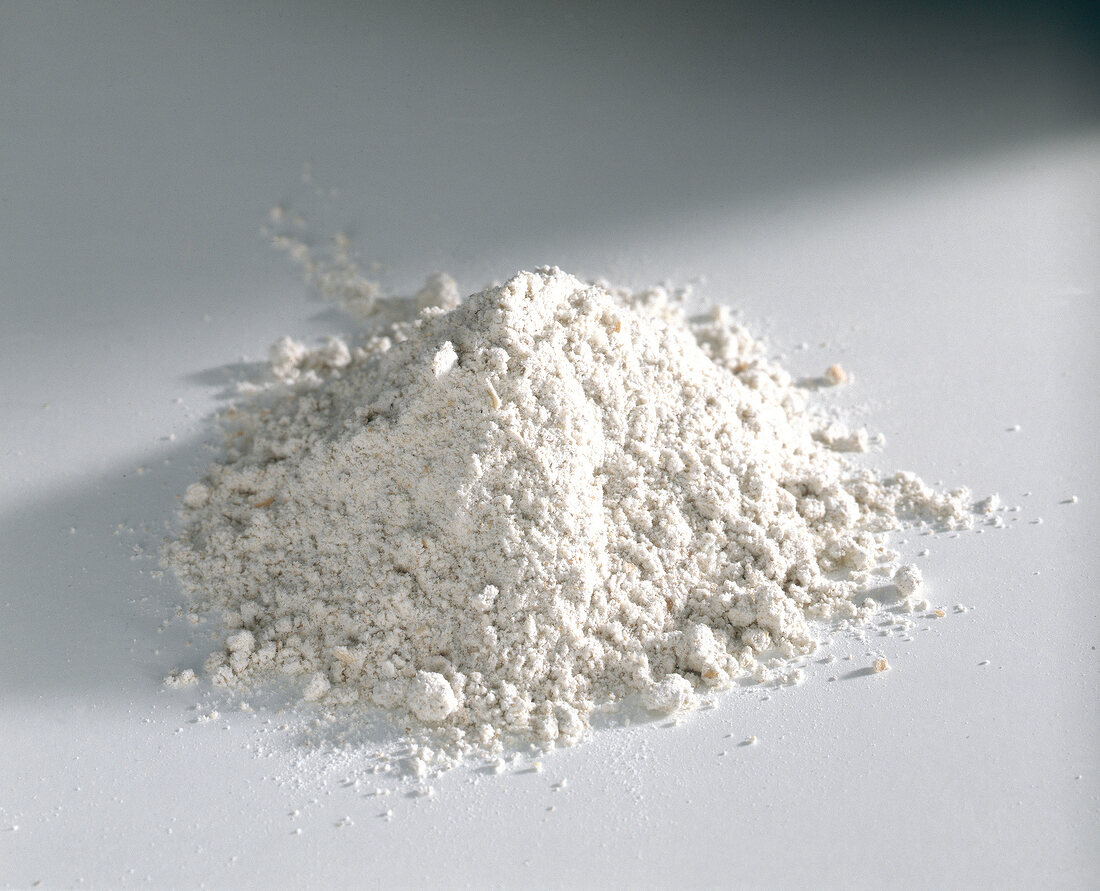 Heap of whole wheat flour on white background