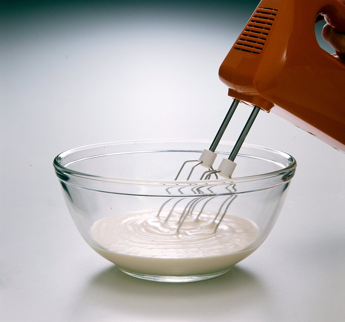 Cream being beaten with beater in bowl