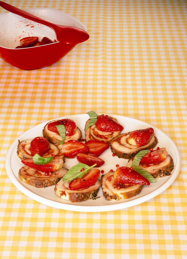 Slices of pork topped with strawberries on plate