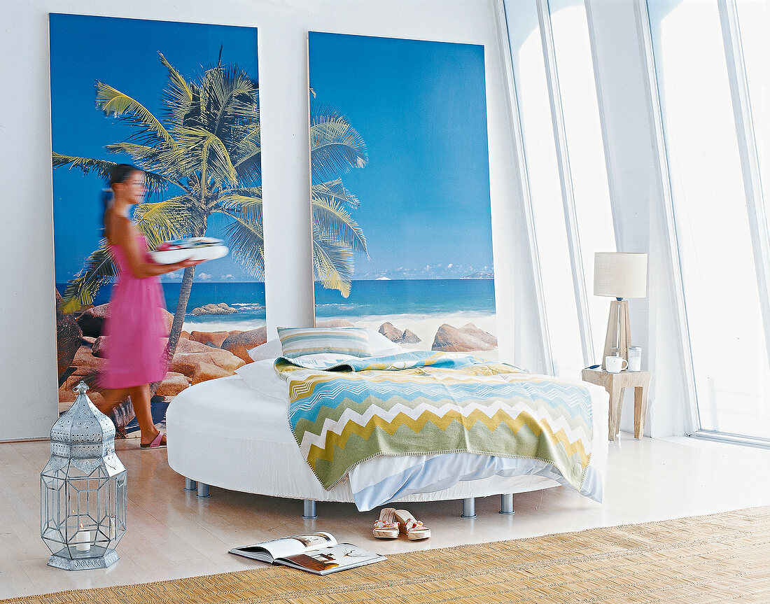 White round bed in front of palm and beach images in bedroom