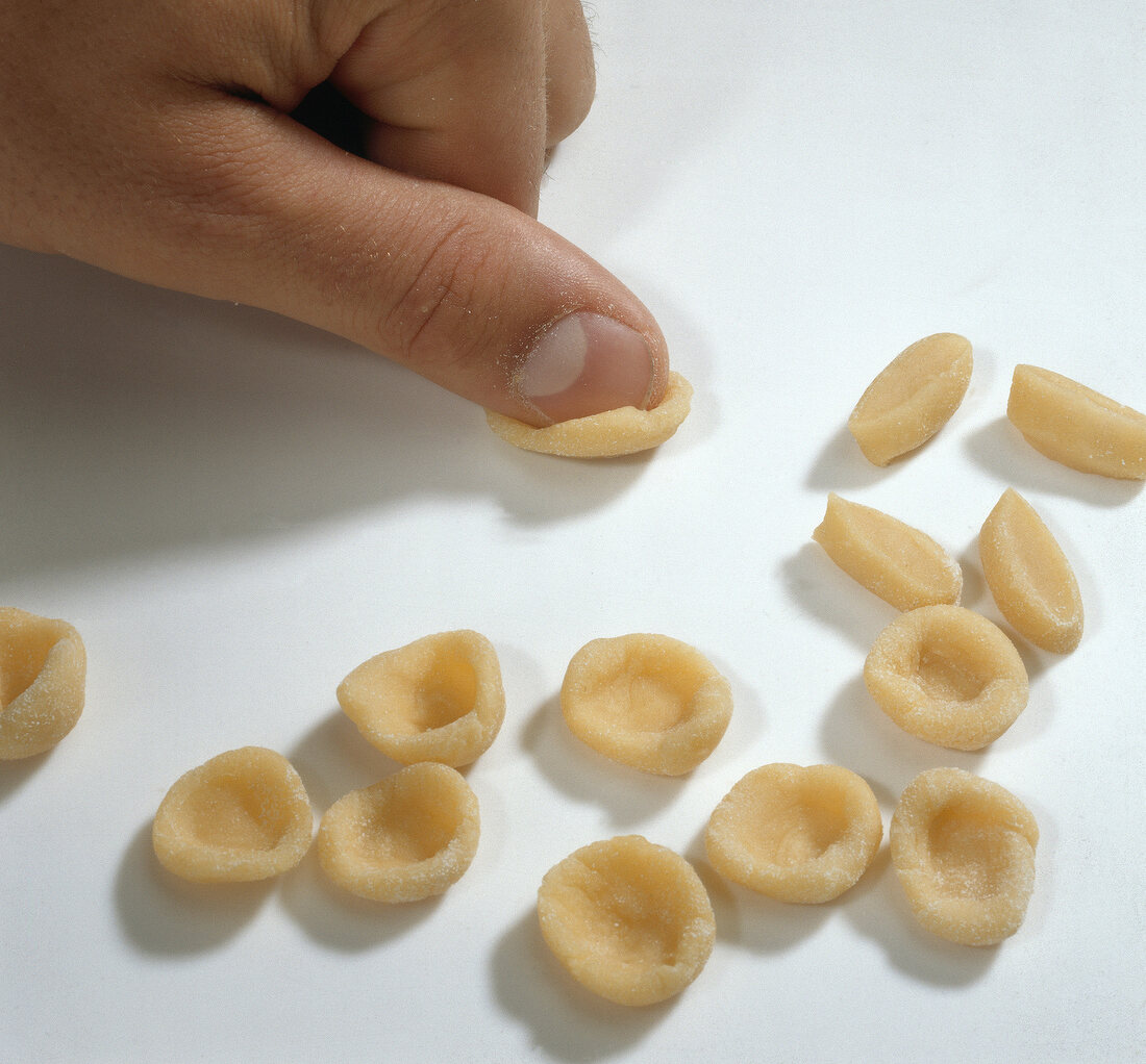 Close-up of thump pressing dough pieces for preparing orecchiette pasta, step 3