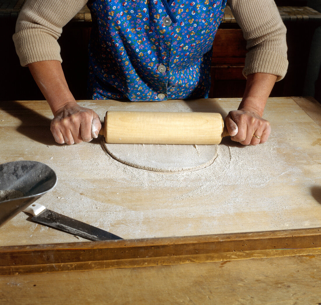 Woman rolling buckwheat dough on table, step 3